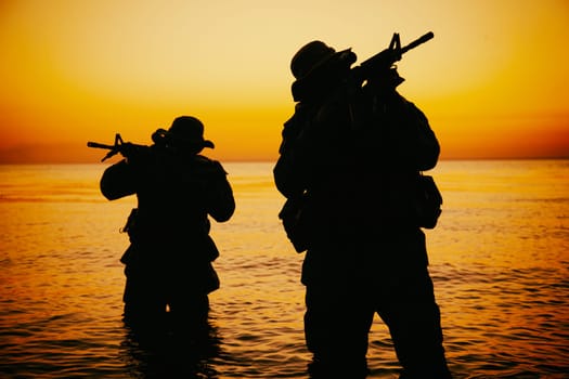 Two commando soldiers, army special operations fighters aiming assault rifles while coming out from water on shore at sunset or dawn. Coast guard shooters landing on sea coast, sneaking in water