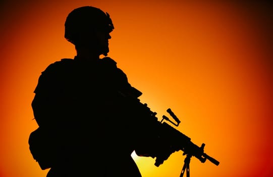 Silhouette of army infantry soldier, commando in combat helmet, armed light machine gun, standing on background of ocean horizon and sunset. Marine Corps rifleman, special forces shooter on sea shore