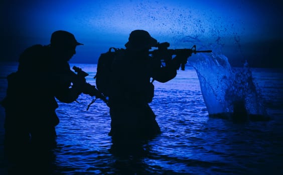Army soldiers team, special operation forces infantrymen landing on seacoast, aiming and shooting with service rifle during firefight on shore at evening or morning time. Military amphibious operation