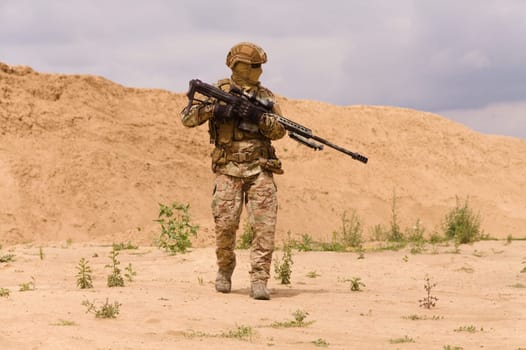 Equipped and armed special forces soldier with rifle in the desert during the military operation.