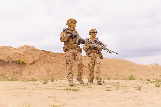 Two soldiers with rifles during army operation in the desert