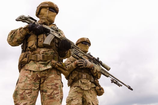 Two special forces soldiers with rifles against sky background, space for text
