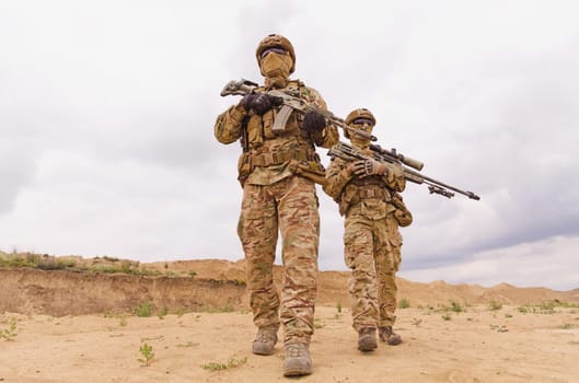 Equipped and armed special forces soldiers with rifles during military operation in the desert