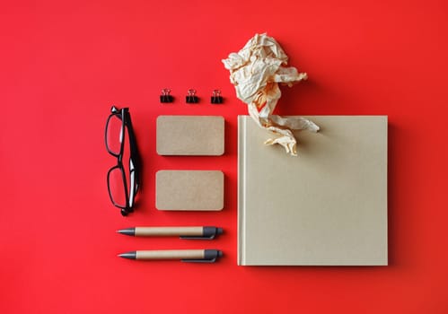 Blank corporate identity template on red paper background. Photo of blank kraft stationery set. Mockup for design presentations and portfolios. Flat lay.