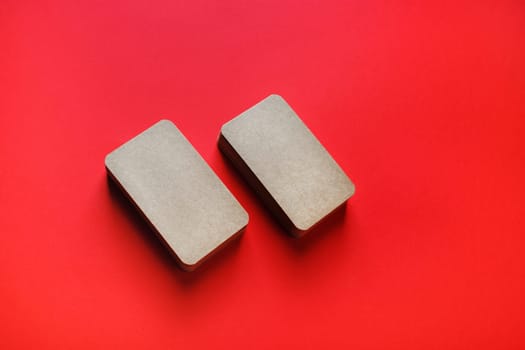Photo of blank kraft business cards on red paper background. Template for branding identity.