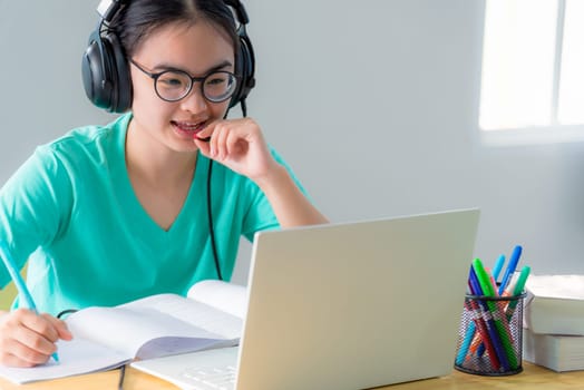 Asian woman looking to talk video conference calling on a laptop computer girl students speak respond with headset microphone class university learning internet online distance education from home