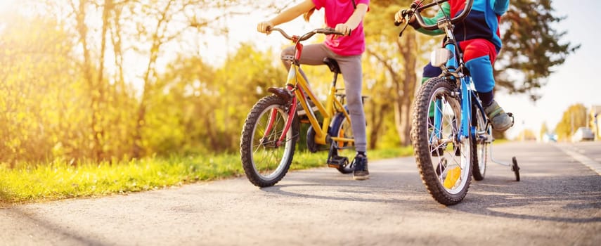 Cute children riding on bicycles on asphalt road in summer. Concept of friendship between people.