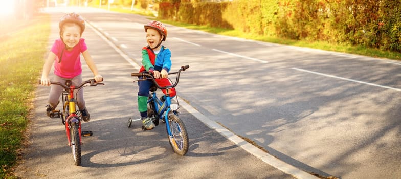Cute children riding on the bicycles at asphalt road in summer. Concept of friendship between people.