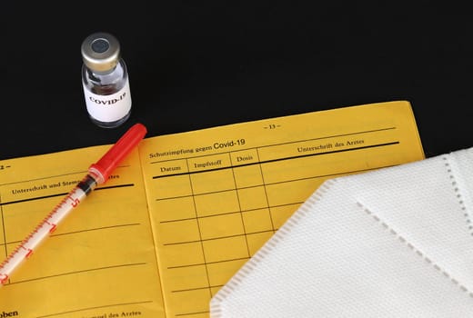 One vaccination against Covid-19. Vaccination certificate, vaccination bottle, syringe and FFP2 mask.