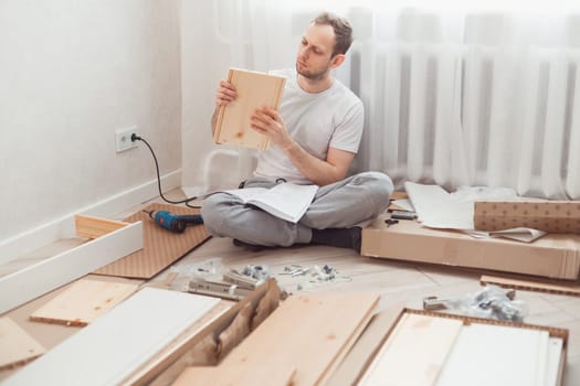 Man self-assemblies wooden furniture at home without master. Read instructions. Man reading instructions. Diy concept