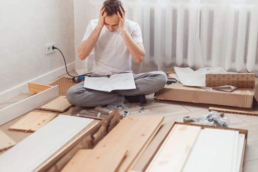 Bewildered man assembling wooden furniture. Difficulties and disadvantages of self-assembly of furniture at home without a master. Man reading instructions and misunderstand what to do the next.