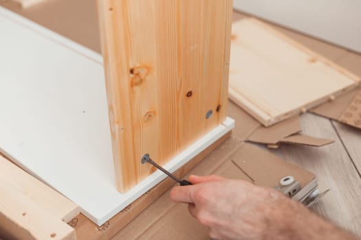 Assembling wooden furniture manually with screwdriwer.