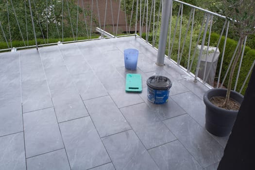 Tiler laying  tiles on the floor of a balcony and grouted.