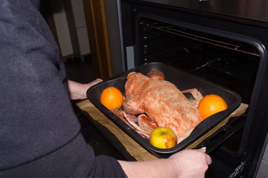 Roast goose stuffed with baked apples and oranges in a frying pan that is pushed in an oven, festive Christmas recipe. Top view with copy space.