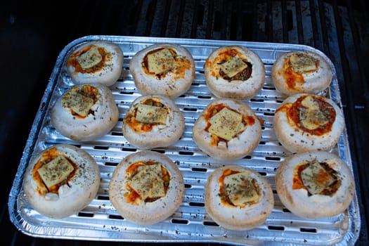 Stuffed portobello mushrooms stuffed with mozzarella and gorgonzola cheese and aromatic herbs on a black background, top view. Vegetarian food