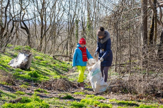 Family collects trash in the forest in a big bag for recycling