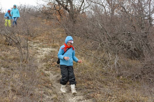 A girl runs down the path from the mountain, in the background a girl with another girl gently descend from the mountain