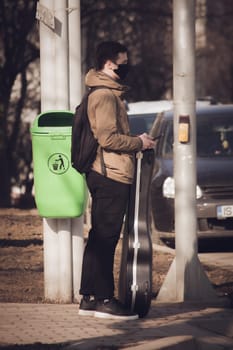 Iasi - Romania - 13th March 2021: Teenager student waiting to cross the street with a guitar in hands