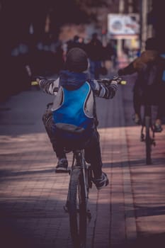 Young boy doing a wheelie with his bike on the sidewalk