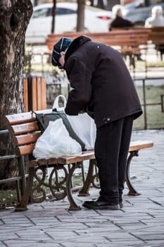 Old man organizing his luggage on a bench in iasi, Romania