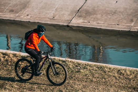 Woman riding a bike next to a river during a sunny day