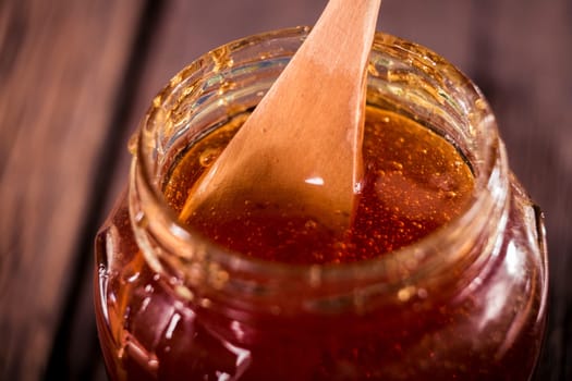 Honey dripping from a wooden honey dipper   on black background