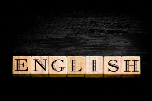 Word English.Wooden small cubes with letters isolated on black background.Concept image.
