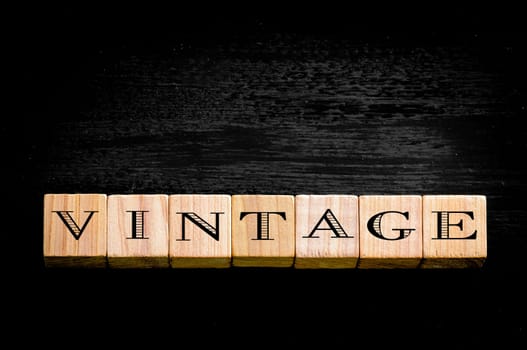 Word Vintage.Wooden small cubes with letters isolated on black background.Concept image.