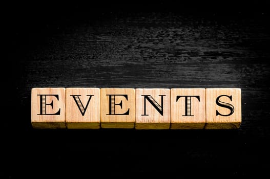 Word Events. Wooden small cubes with letters isolated on black background.Concept image.