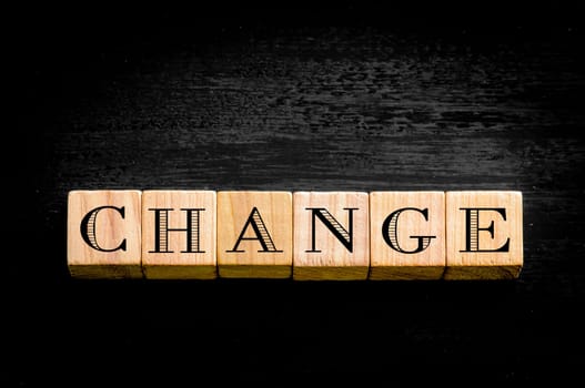 Word Change. Wooden small cubes with letters isolated on black background.Concept image.