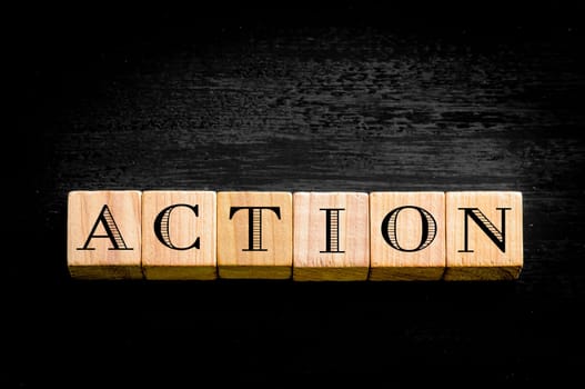 Word Action. Wooden small cubes with letters isolated on black background.Concept image.