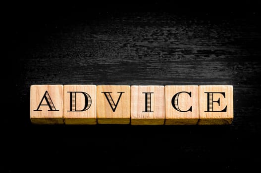 Word Advice. Wooden small cubes with letters isolated on black background.Concept image.