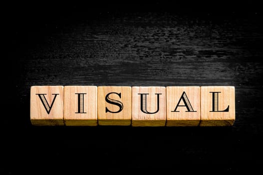 Word Visual. Wooden small cubes with letters isolated on black background.Concept image.