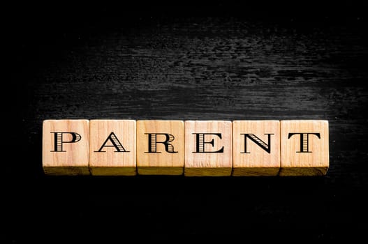 Word Parent. Wooden small cubes with letters isolated on black background.Concept image.