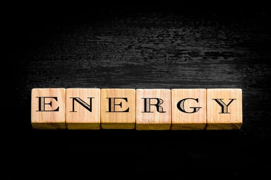 Word Energy. Wooden small cubes with letters isolated on black background.Concept image.