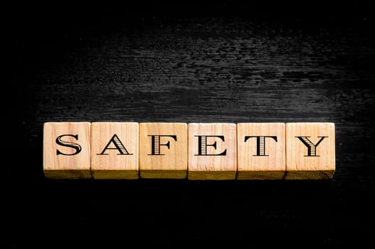 Word Safety. Wooden small cubes with letters isolated on black background.Concept image.