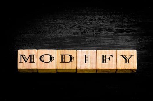 Word Modify. Wooden small cubes with letters isolated on black background.Concept image.