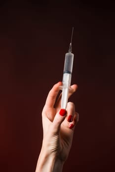 A syringe in a hand is isolated on black background