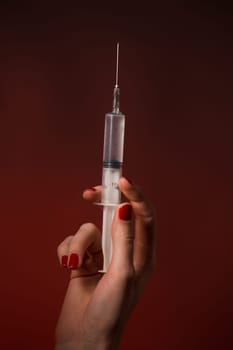 A syringe in a hand is isolated on black background