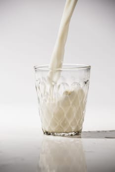 pouring milk in a glass isolated against white background