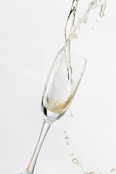 White wine splashing out of glass, isolated on white background