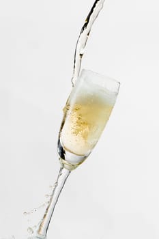 White wine splashing out of glass, isolated on white background