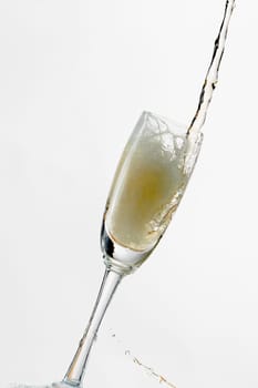 White wine splashing out of glass, isolated on white background