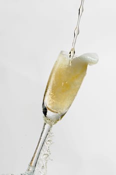 White wine splashing out of glass, isolated on white background