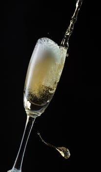 Glass of champagne with splash, isolated on black background