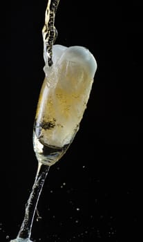 Glass of champagne with splash, isolated on black background