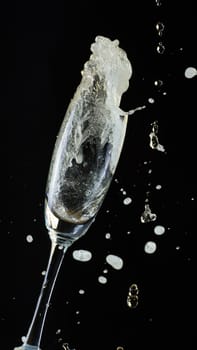 Glass of champagne with splash, isolated on black background