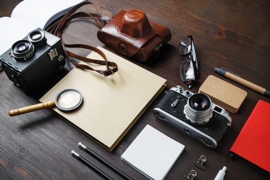 Planning vacation trip with retro camera and vintage stationery on wooden background.