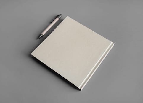 Photo of closed blank kraft brochure and pen on gray paper background. Template for placing your design.