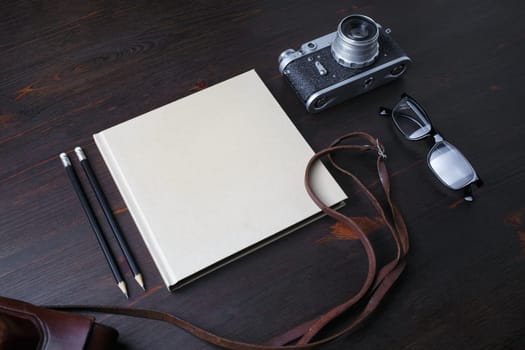 Vintage stationery and retro photo camera on wooden background.